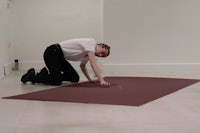 a man kneeling down on a red rug in an empty room