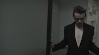 a man in a black suit standing next to a pole