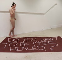 a man in a bikini standing next to a sign that says do you want to be made healed?